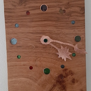May include: A wooden clock with a copper star and hands, and a variety of coloured glass circles around the face.