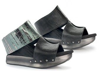 May include: A pair of black leather sandals with a silver platform sole. One sandal features a wide, textured strap in a teal and silver pattern. The other sandal has a solid black strap. Both have silver studs along the sole.