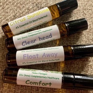 May include: Four glass rollerball bottles with black caps and white labels. The labels have different names and descriptions, including "Citrus Sunshine", "Clear Head", "Float Away", and "Comfort".