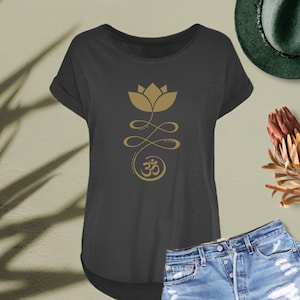 May include: A dark grey t-shirt featuring a gold lotus flower and Om symbol graphic. The shirt has a relaxed fit and a slightly longer length at the back.