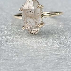 May include: A gold ring with a clear, faceted, raw crystal stone set in the centre.