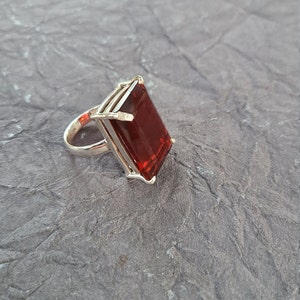 K&ouml;nnte beinhalten: Ein silberner Ring mit einem gro&szlig;en, rechteckigen, roten Edelstein.