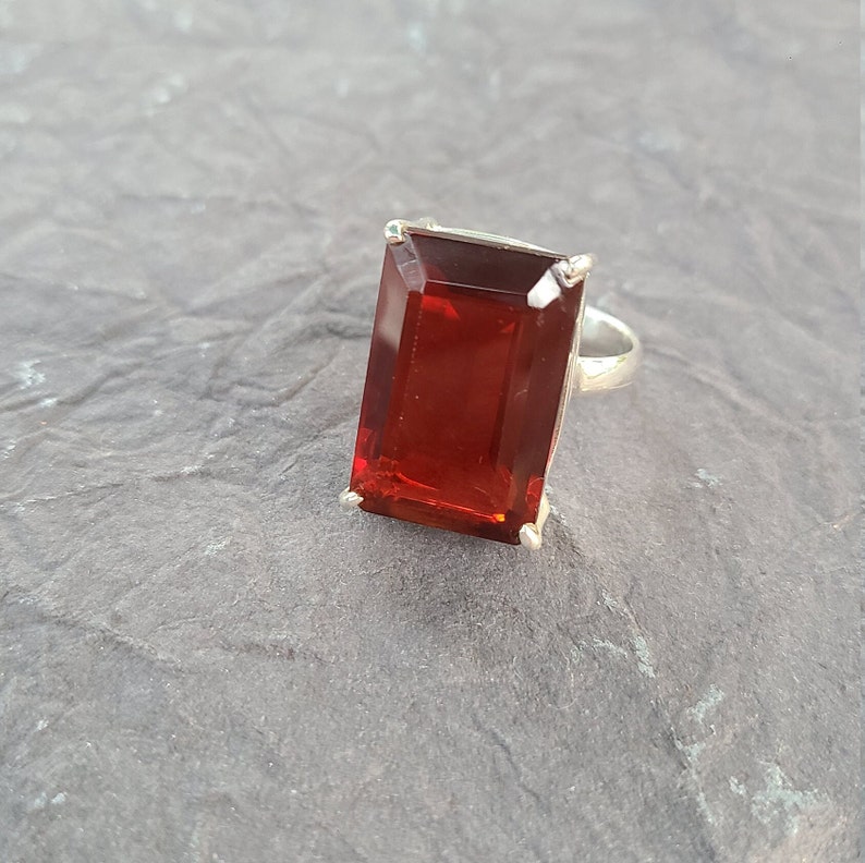 K&ouml;nnte beinhalten: Ein silberner Ring mit einem gro&szlig;en, rechteckigen, roten Edelstein.