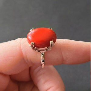 Könnte beinhalten: Ein silberner Ring mit einem großen, ovalen, leuchtend roten Edelstein.