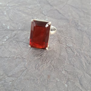 K&ouml;nnte beinhalten: Ein silberner Ring mit einem gro&szlig;en, rechteckigen, roten Edelstein.