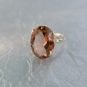 Könnte beinhalten: Ein silberner Ring mit einem großen, ovalen, hellbraunen Edelstein.