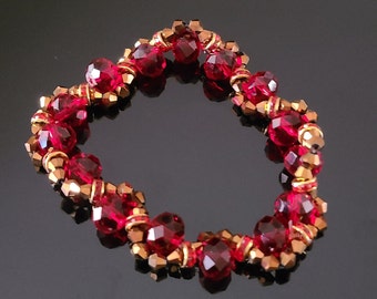 May include: A red and gold beaded bracelet with a twisted design. The bracelet is made with small, faceted beads.