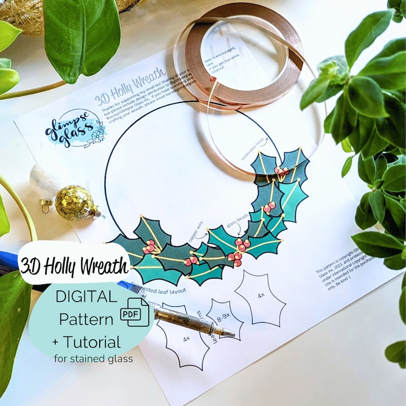 stained glass holly wreath pattern on table with copper foil and plants. Festive tree ornaments shown with a four page pdf tutorial. downloadable holiday pattern, 3D stained glass wreath