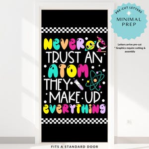 K&ouml;nnte beinhalten: Schwarze T&uuml;rverkleidung mit dem Text "Never Trust An Atom They Make Up Everything" in bunten Buchstaben. Das Design umfasst wissenschaftliche Grafiken und einen karierten Rand. Der Text "Fits a Standard Door" steht unten.