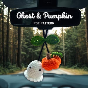 May include: A crocheted car charm with a white ghost and an orange pumpkin. The charm is suspended from a green leaf design. The text "Ghost & Pumpkin PDF Pattern" is displayed on the rearview mirror, against a forest backdrop.