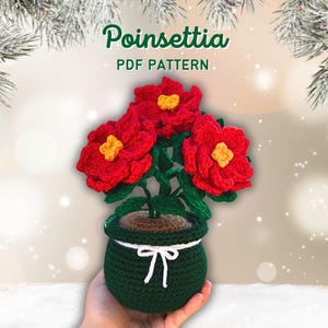 May include: A crocheted poinsettia plant in a green pot with a white bow. The plant has three red flowers with yellow centers and green leaves. The text "Poinsettia PDF PATTERN" is at the top.