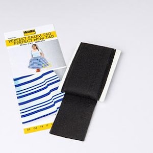 May include: A black hem tape roll with a white backing is displayed next to a product package. The package features the text "PERFEKT SAUM T40 PERFECT HEM T40" and an image of a skirt. The package also shows blue and white striped fabric.