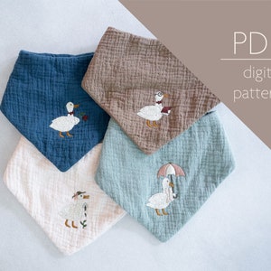 May include: Four different fabric bibs with embroidered duck designs. The bibs are in blue, brown, white, and light blue. The designs include a duck with a flower, a duck with glasses, a duck with an umbrella, and a duck with a hat.