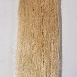 May include: A long, straight piece of blonde human hair extensions with a weft sewn in. The hair is attached to a clip for easy application.