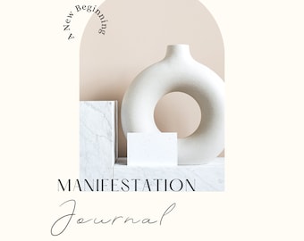 Op de afbeelding: Een witte keramische vaas met een ringvorm staat op een wit marmeren platform. De achtergrond is licht perzikkleurig met de tekst "A New Beginning" in een cirkel. De tekst "MANIFESTATION Journal 2023 Intentions" staat onder de vaas.