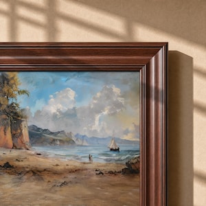 May include: A framed landscape painting depicting a coastal scene with a sandy beach, rocky cliffs on the left, and a sailboat on the water under a blue sky with white clouds. Two small figures stand on the shore near the water's edge.