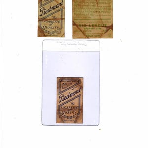 May include: Vintage baseball cards featuring "Piedmont" cigarette advertising and a card of George Herman "Babe" Ruth. The cards are in a protective sleeve. The "Piedmont" cards have text that reads "The Cigarette of Quality".