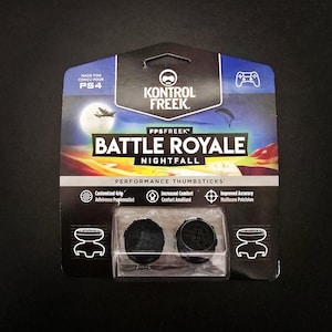 May include: A package of Kontrol Freek FPS Freek Battle Royale Nightfall performance thumbsticks for PS4. The package features a night sky graphic with a plane and a parachute. The thumbsticks are black and have a textured surface.