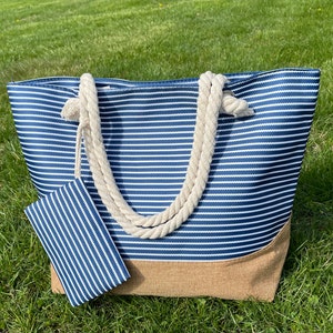 May include: A blue and white striped tote bag with a brown bottom and rope handles. The bag has a matching smaller pouch attached to it.