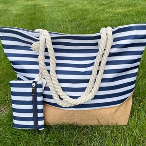 May include: A large striped tote bag with a natural jute bottom and rope handles. A smaller matching zippered pouch is included.