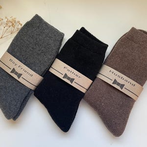 May include: Three pairs of socks with brown paper tags. The tags have a bow tie design and the text "Boy Friend", "Father", and "Husband".