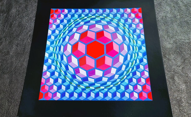 May include: A colorful optical illusion print featuring a sphere made of blue, pink, and red cubes. The sphere is surrounded by a pattern of smaller cubes.
