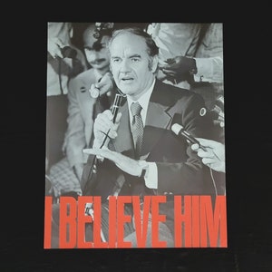 Puede incluir: Una fotografía en blanco y negro de un hombre hablando en un micrófono. El hombre lleva traje y corbata. La fotografía tiene el pie de foto "I BELIEVE HIM".
