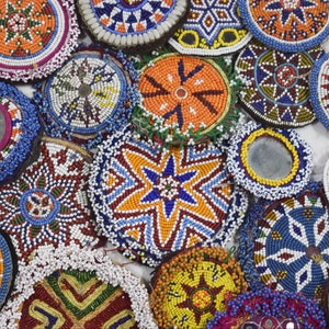 Puede incluir: Una colección de adornos redondos, de cuentas, decorativos con intrincados patrones en varios colores, incluyendo azul, rojo, naranja, amarillo y blanco.