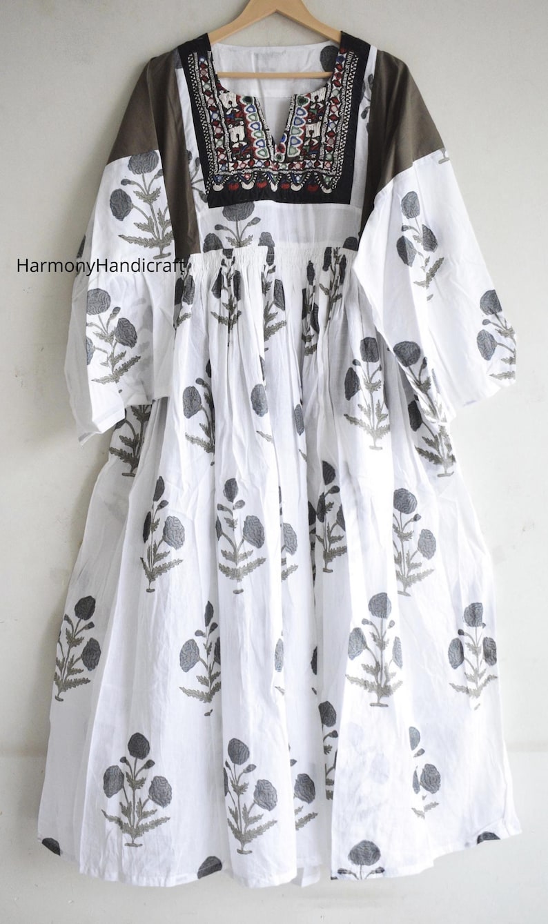 Puede incluir: Vestido de algod&oacute;n blanco con estampado floral gris. El vestido presenta un escote bordado y paneles de hombro marrones. Las mangas son de tres cuartos. El texto "HarmonyHandicraft" es visible en el lado izquierdo del vestido.