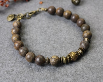 May include: A brown wood beaded bracelet with gold metal accents. The bracelet has a clasp closure.