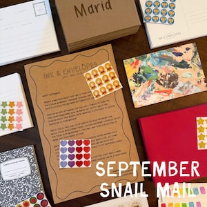May include: A stationery set featuring a brown paper letter with the text Ink & Envelopes Snail Mail Club, a composition notebook, various sticker sheets with stars, hearts, and trophies, a colorful abstract postcard, and a red folder.