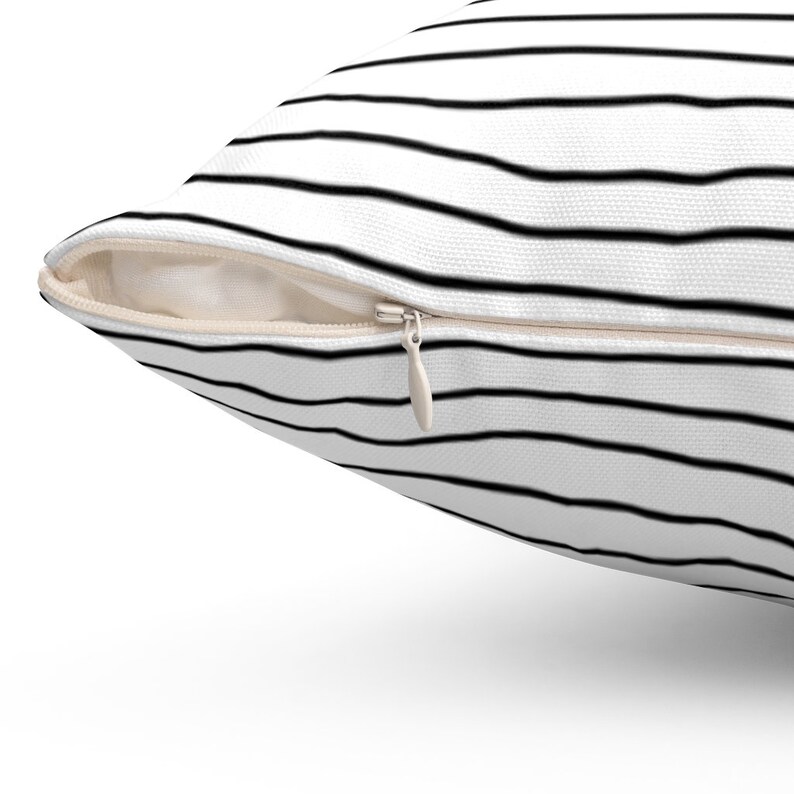 May include: A white pillow with black horizontal stripes and a zipper closure.