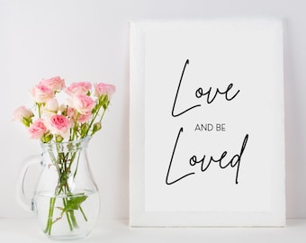 Könnte beinhalten: Ein durchsichtiger Glaskrug gefüllt mit hellrosa Rosen neben einem weißen rechteckigen Rahmen, der den schwarzen Text Love AND BE Loved in einer Kombination aus Schreib- und serifenloser Schrift auf weißem Grund enthält.
