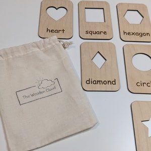 Peut inclure: Cartes de formes en bois avec des d&eacute;coupes en forme de c&oelig;ur, carr&eacute;, hexagone, croix, losange, cercle et &eacute;toile. Les cartes sont en bois clair et comprennent les noms des formes. Un sac en toile avec le logo "The Wooden Cloud" est inclus.