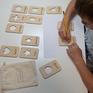Peut inclure: Cartes de tra&ccedil;age de formes en bois avec des formes d&eacute;coup&eacute;es et des &eacute;tiquettes imprim&eacute;es. Comprend un c&oelig;ur, une &eacute;toile, un losange, un ovale, un rectangle, un carr&eacute;, un pentagone, un triangle, un cercle, un hexagone, une croix et un octogone. Un enfant trace la forme carr&eacute;e avec un crayon.