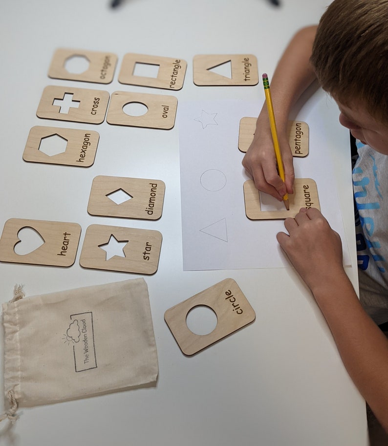Peut inclure: Cartes de tra&ccedil;age de formes en bois avec des formes d&eacute;coup&eacute;es et des &eacute;tiquettes imprim&eacute;es. Comprend un c&oelig;ur, une &eacute;toile, un losange, un ovale, un rectangle, un carr&eacute;, un pentagone, un triangle, un cercle, un hexagone, une croix et un octogone. Un enfant trace la forme carr&eacute;e avec un crayon.