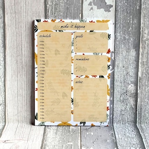 May include: A white dry-erase board with a floral pattern. The board is divided into four sections: schedule, goals, reminders, and notes. The text "make it happen" is at the top of the board.