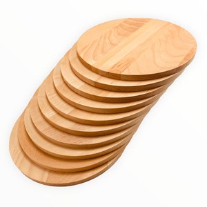 May include: A stack of round wooden cutting boards, arranged in a graduated size, with the largest board at the top and the smallest board at the bottom.