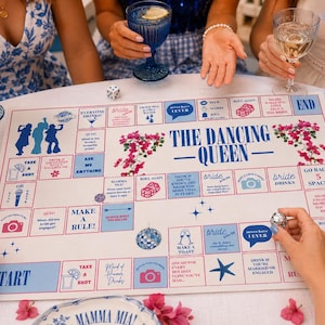 Puede incluir: Un juego de mesa blanco con detalles azules y rosas, titulado "The Dancing Queen". El tablero del juego presenta varios cuadrados con instrucciones e ilustraciones. También hay bebidas y arreglos florales.