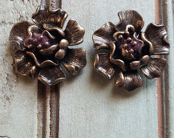 May include: A pair of gold-tone flower-shaped earrings with a purple velvet center.