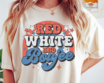 May include: A white t-shirt with a red, white and blue graphic that says "Red White and Boujee" in a retro font.