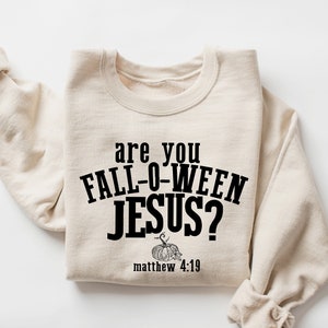 May include: A beige sweatshirt with the text "are you FALL-O-WEEN JESUS?" in black. Below the text is a small black and white image of a pumpkin and the text "matthew 4:19".