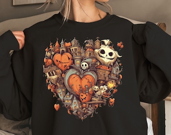 May include: Black sweatshirt with a heart-shaped design featuring a spooky town, pumpkins, and a Jack Skellington-like character.