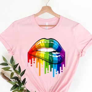 May include: Pink t-shirt with a rainbow-colored dripping lips graphic.