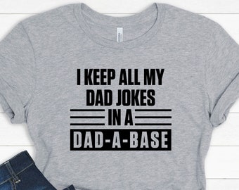 May include: A gray t-shirt with black text that reads "I keep all my dad jokes in a dad-a-base".