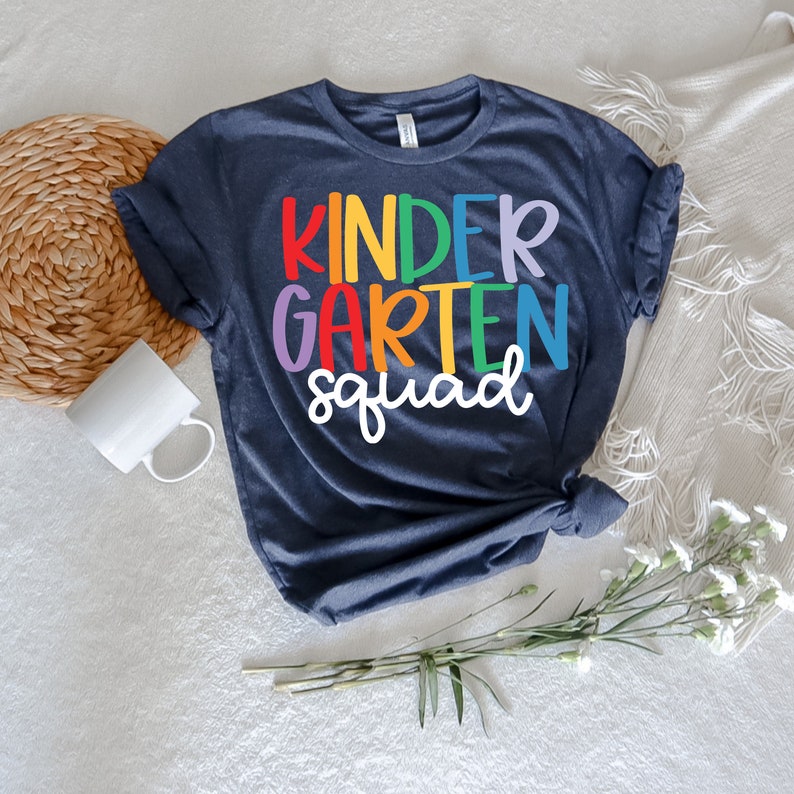 May include: A dark blue t-shirt with the text "kindergarten squad" in rainbow colors.