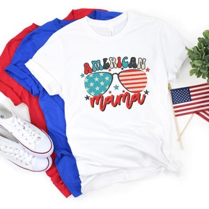 Puede incluir: Camiseta blanca con un gr&aacute;fico de gafas de sol rojo, blanco y azul con el texto "American mama" debajo.