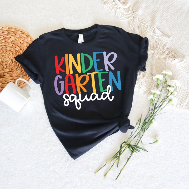 May include: Black t-shirt with the text "Kindergarten Squad" in rainbow colors.