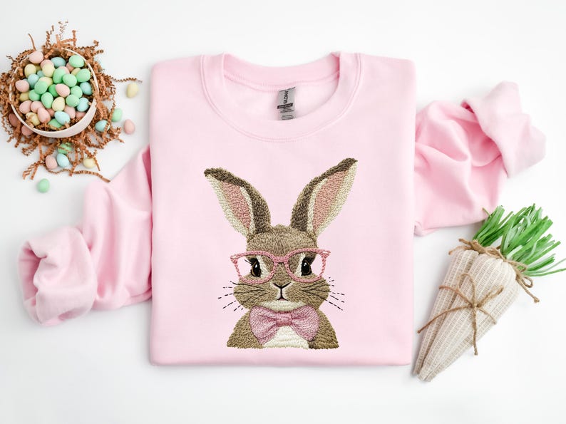 May include: Pink sweatshirt with an embroidered brown bunny wearing pink glasses and a pink bow tie.