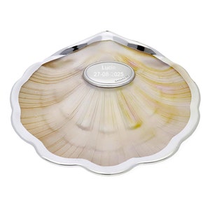 May include: A silver shell-shaped dish with a mother-of-pearl interior. The dish has a small silver plaque in the center with the inscription "Lucia 27-08-2025".